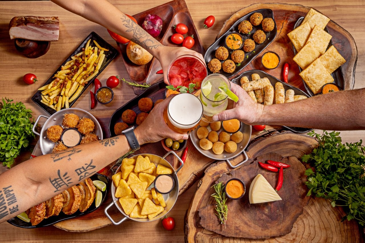 Mesa do Giggs com porções, bebidas e amigos brindando